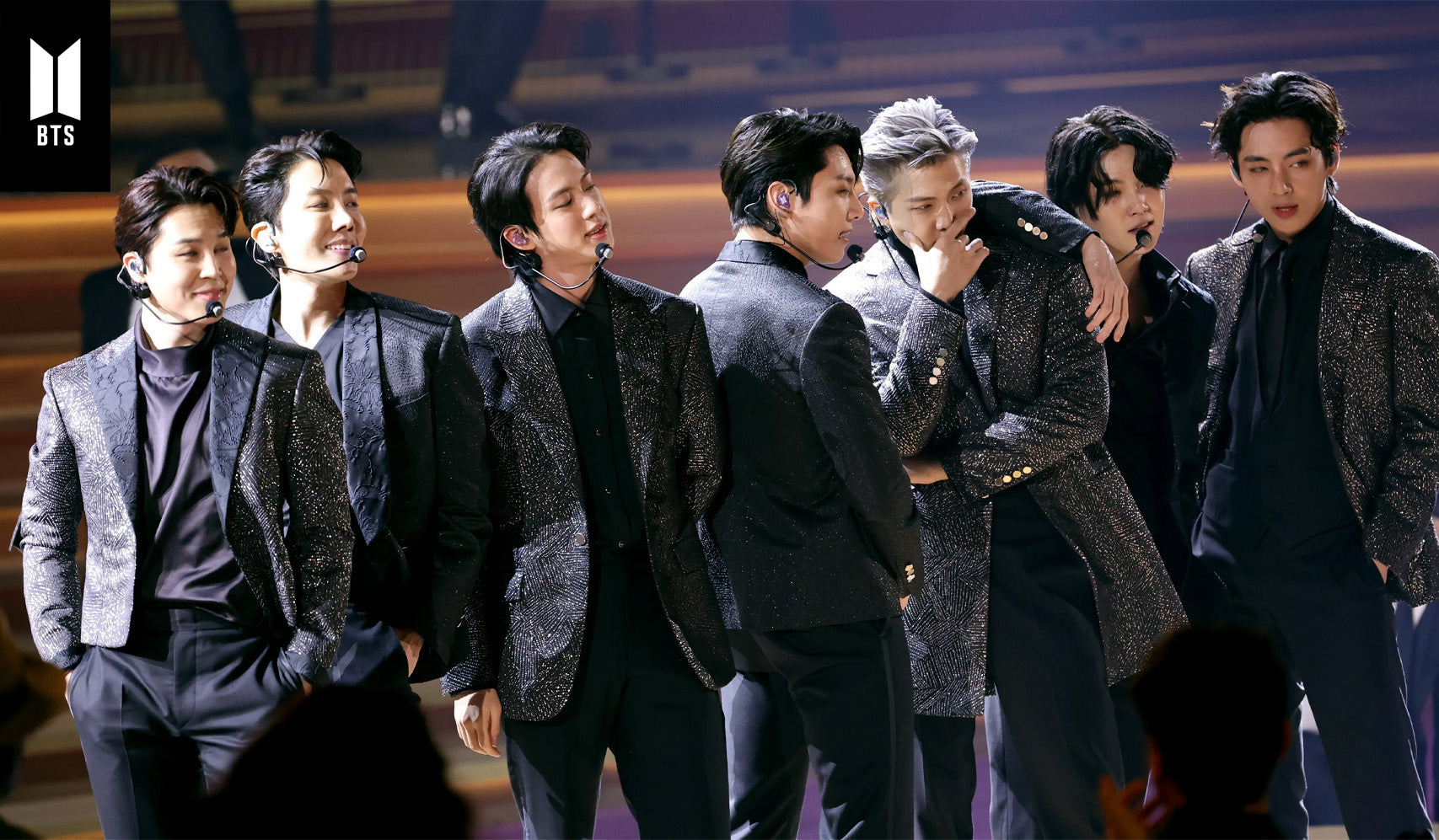 Group of performers on stage in matching glittery outfits during a live performance.
