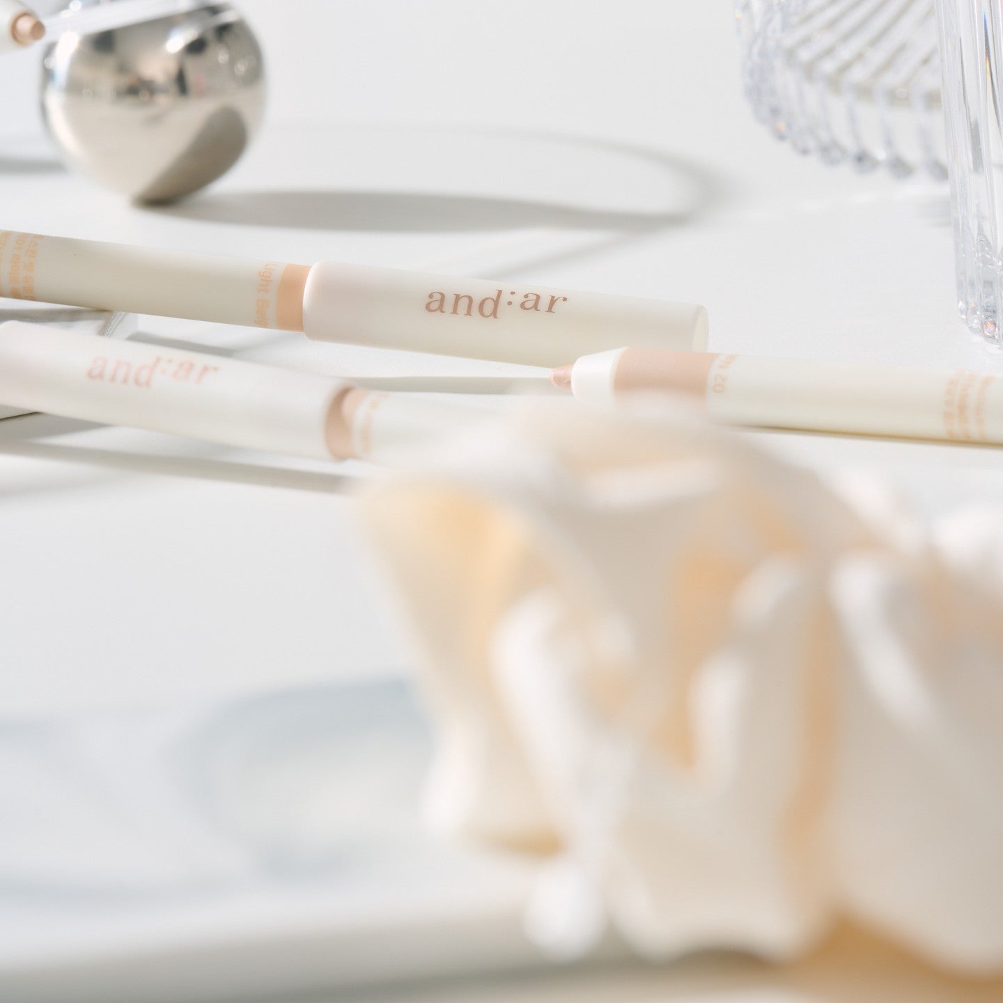 Close-up of the AND:AR Soft Skinfit Dual Concealer Pencil on a white surface, showcasing its sleek design and dual-end functionality.