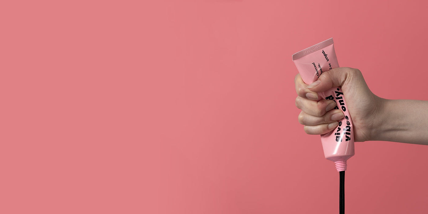 Unveiling the Charm of Korean Skincare: Exploring the UNPA Phenomenon - hand squeezing pink skincare tube against pink background