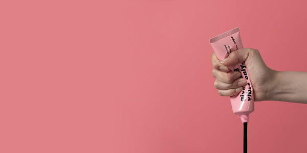 Unveiling the Charm of Korean Skincare: Exploring the UNPA Phenomenon - hand squeezing pink skincare tube against pink background