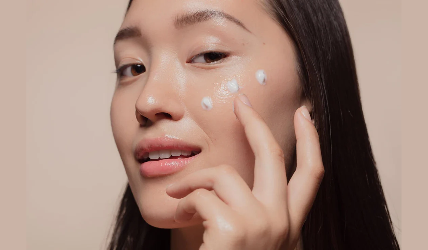 Woman applying cream to face, showcasing ❄️ Cold-Weather Skin Solutions Korean Skincare Picks from KoolSeoul You Need This Winter.