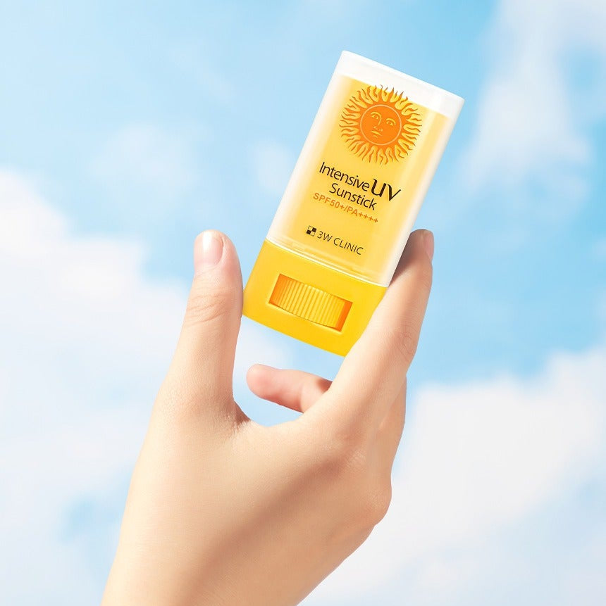 Hand holding 3W CLINIC Intensive UV Sun Sticks 20g against a blue sky background.