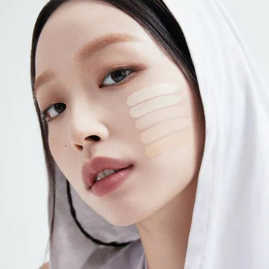 Model with different shades of ABOUT TONE Skin Layer Fit Foundation on cheek for tone matching.