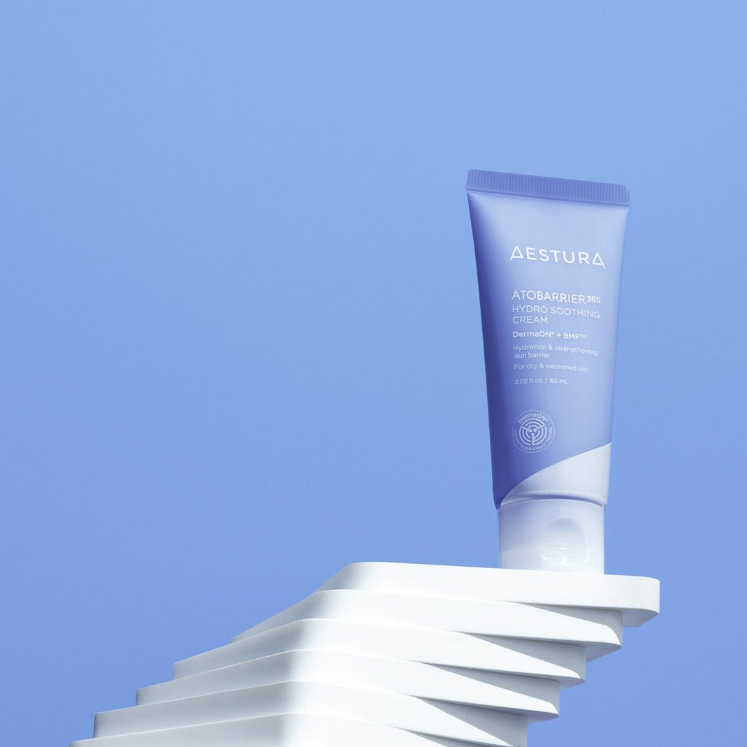 AESTURA Atobarrier 365 Hydro Soothing Cream 60ml tube on abstract white pedestal with blue background