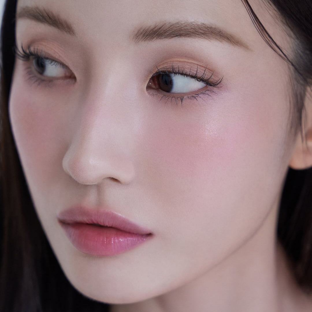 Close-up of a woman's face with natural makeup and subtle glow.