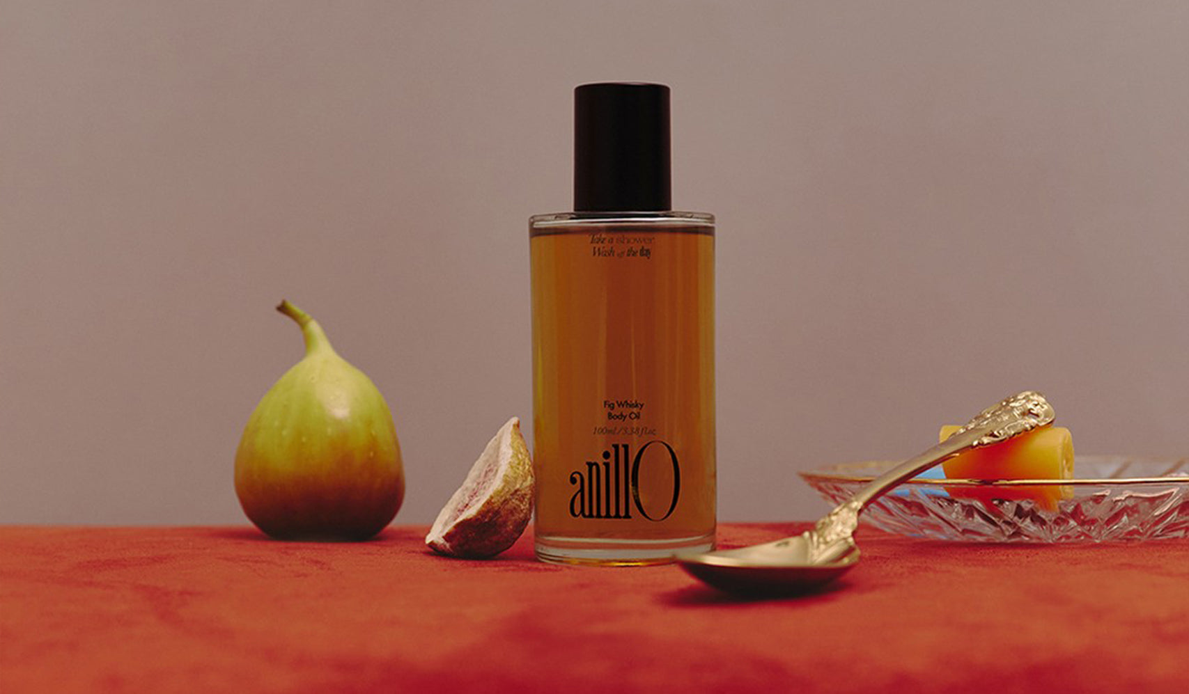 Luxury perfume bottle displayed with fig and dessert, on an elegant red background, conveying sophistication and indulgence.