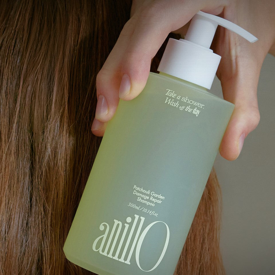 ANILLO Patchouli Garden Damage Repair Shampoo 300ml bottle held near hair for damage repair and nourishment.