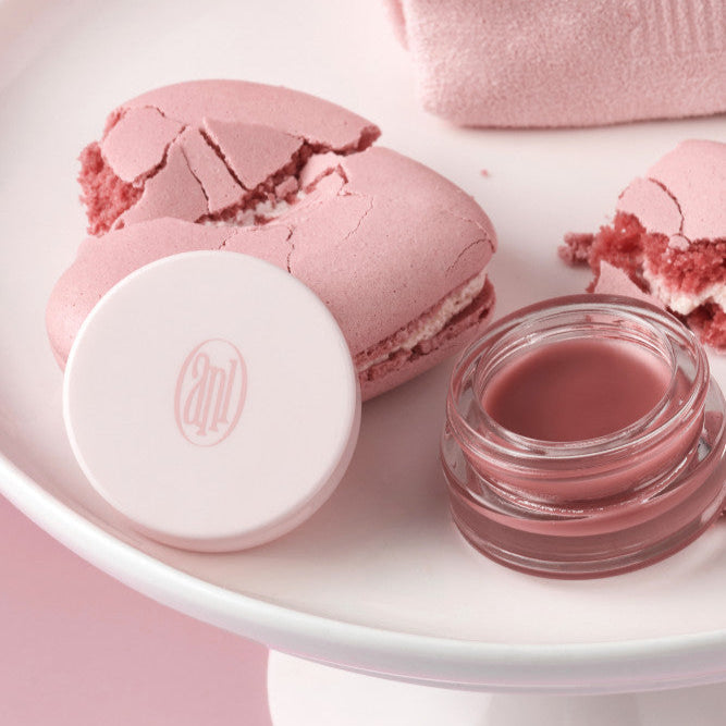 ANILLO Rose Glow Balm jar beside pink macaron and towel for skincare