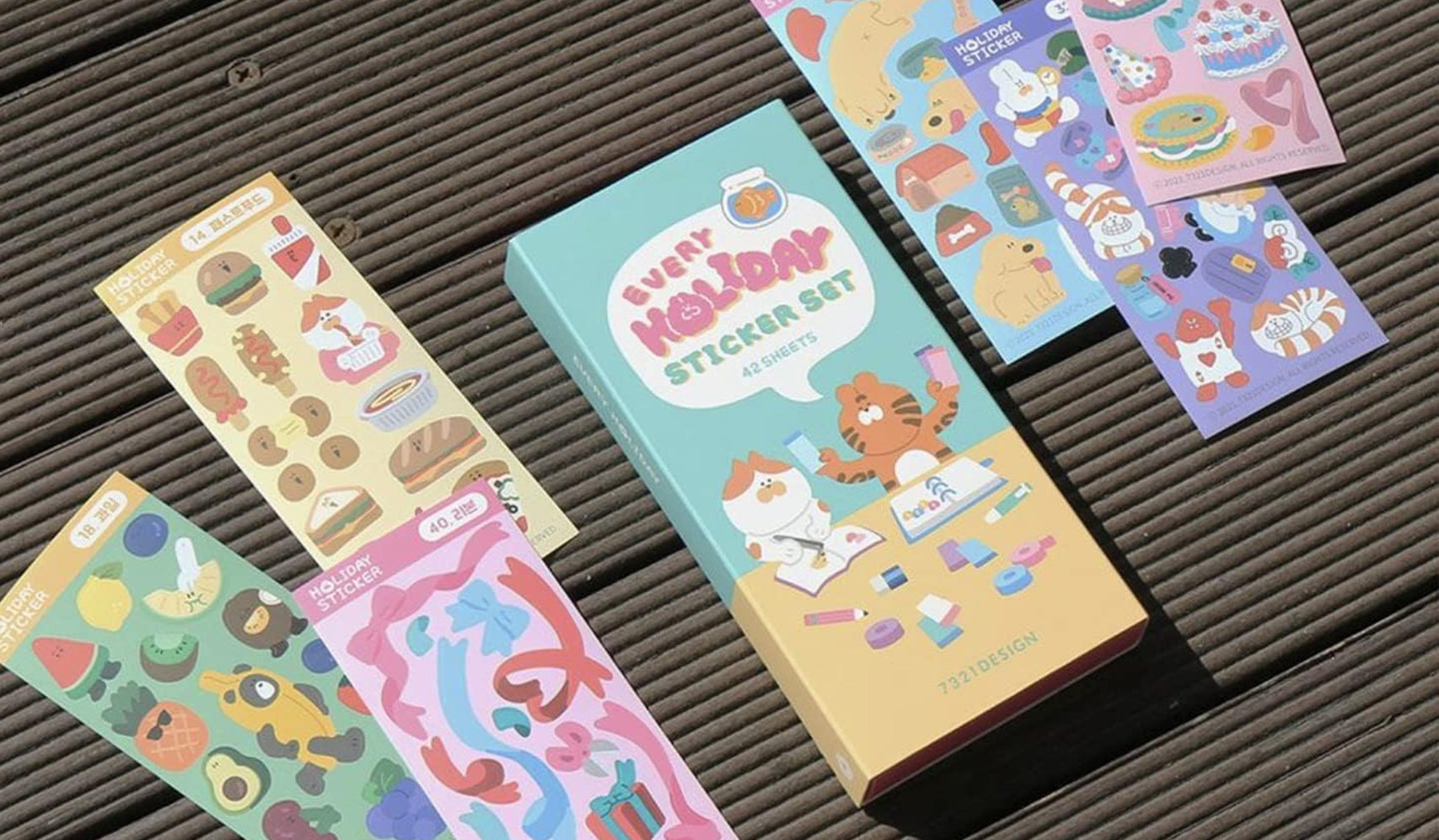 Colorful holiday sticker set featuring cartoon cats and festive illustrations displayed on a wooden surface.