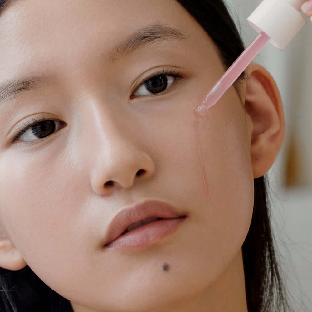 Woman applying ARENCIA Red Smoothie Serum 8 30ml to her face, demonstrating skincare application technique.