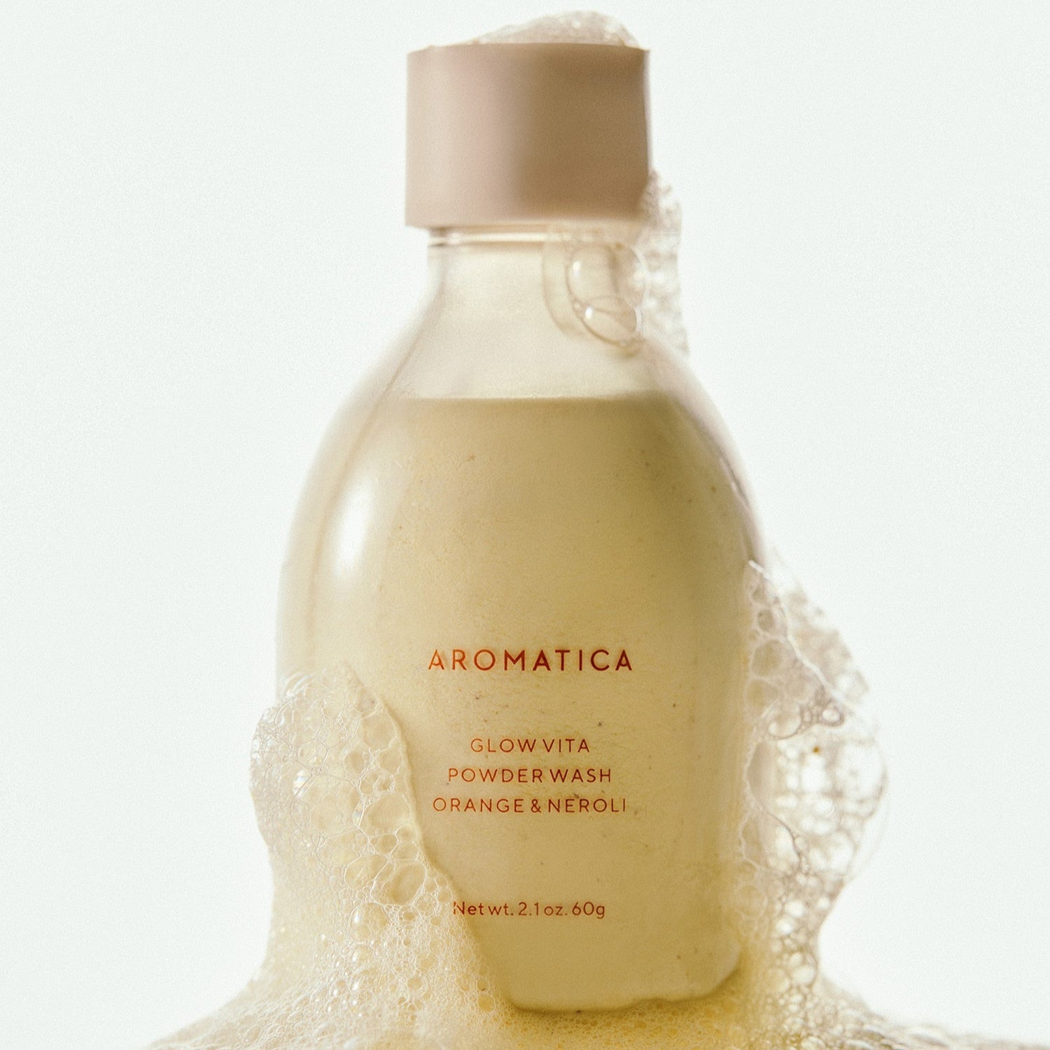 AROMATICA Glow Vita Powder Wash Orange & Neroli 60G with foaming bubbles in a bottle.