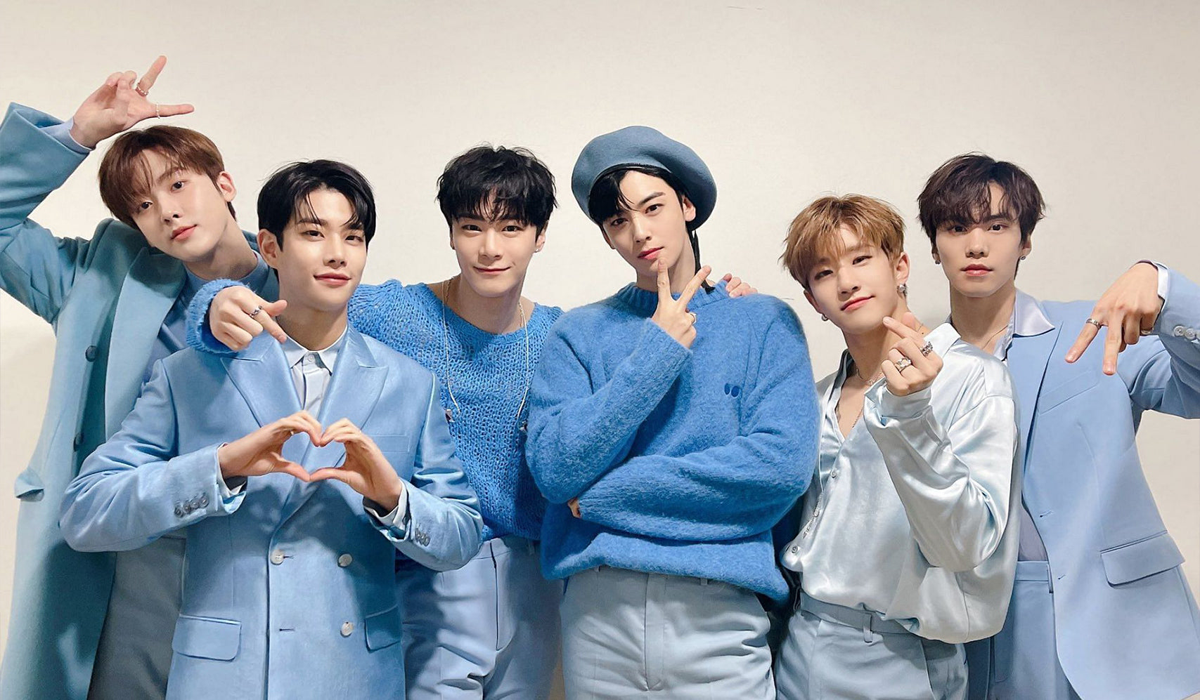 Group of six young men in coordinated blue outfits posing together against a light background.