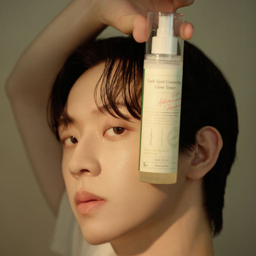 Model holding AXIS-Y Dark Spot Correcting Glow Toner 125ml bottle, skincare product for glowing skin and dark spot correction