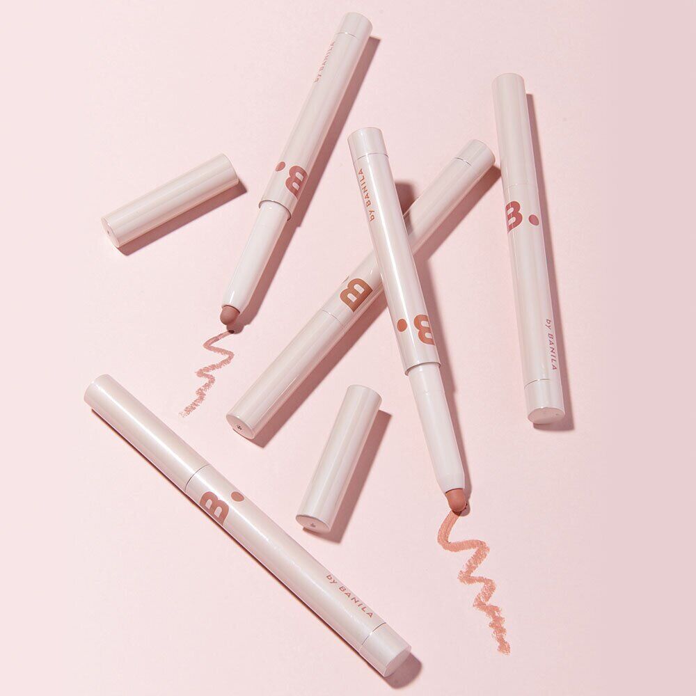 Assorted BANILA CO Smudging Lip Pencil on pink background, showcasing their applicator tips and design.
