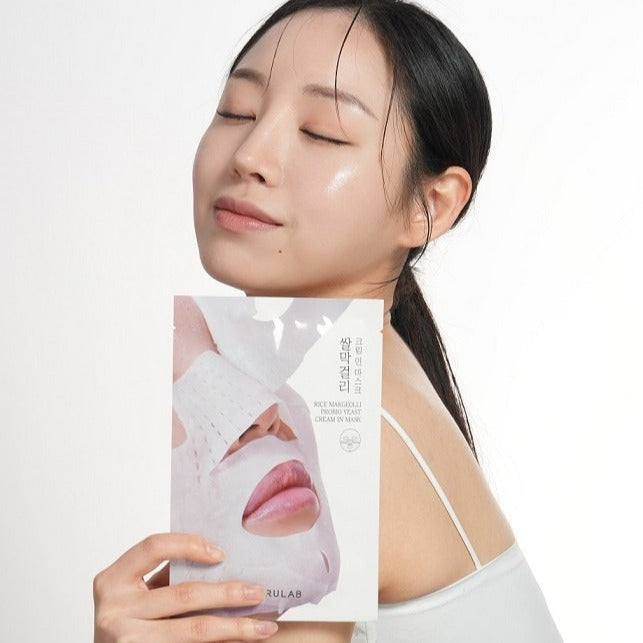 Woman holding BARULAB Rice Makgeolli Probiotic Yeast Cream In Mask 5 Sheets package, showcasing skincare product benefits.