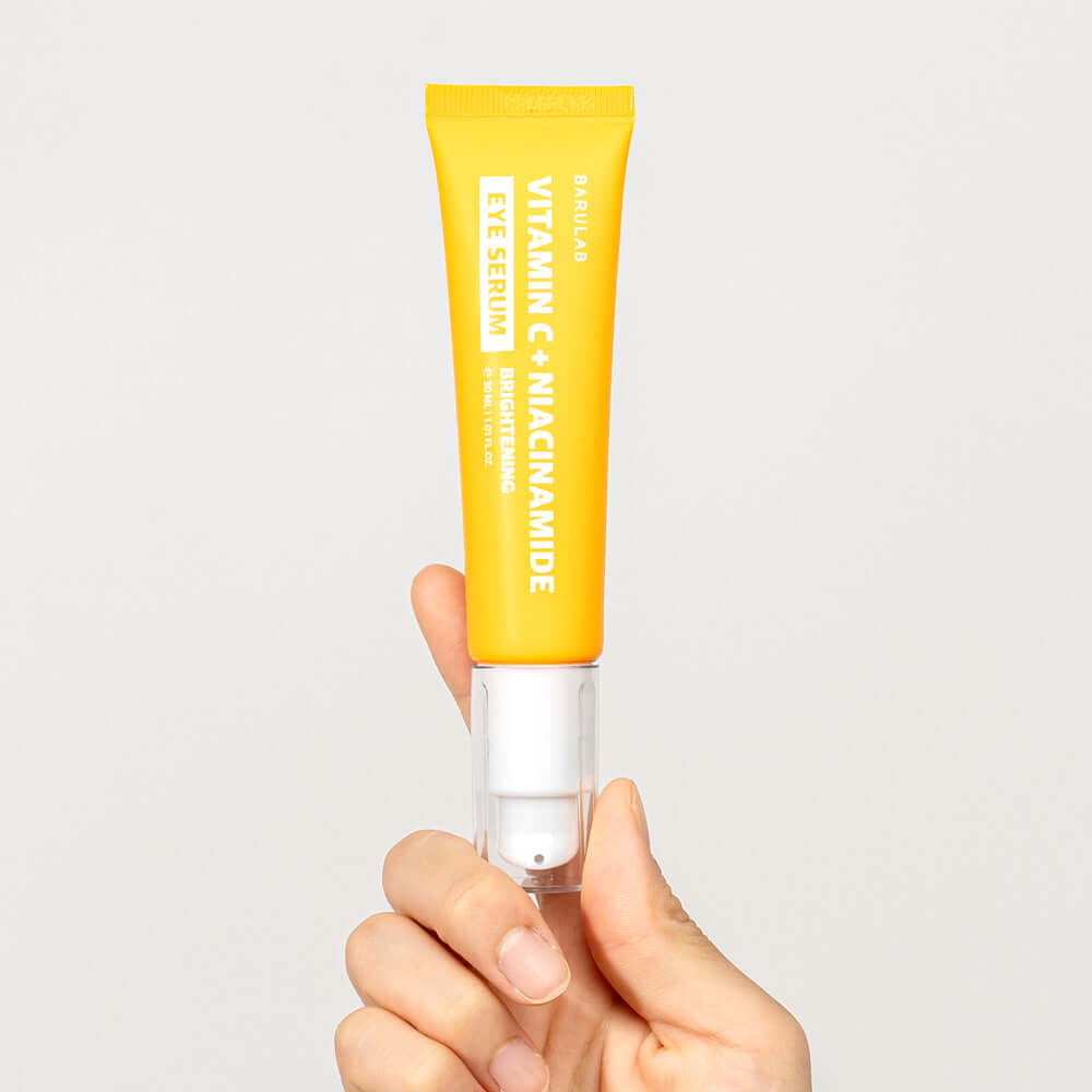 Hand holding BARULAB Vitamin C Niacinamide Whitening Eye Serum 30ml in bright yellow packaging