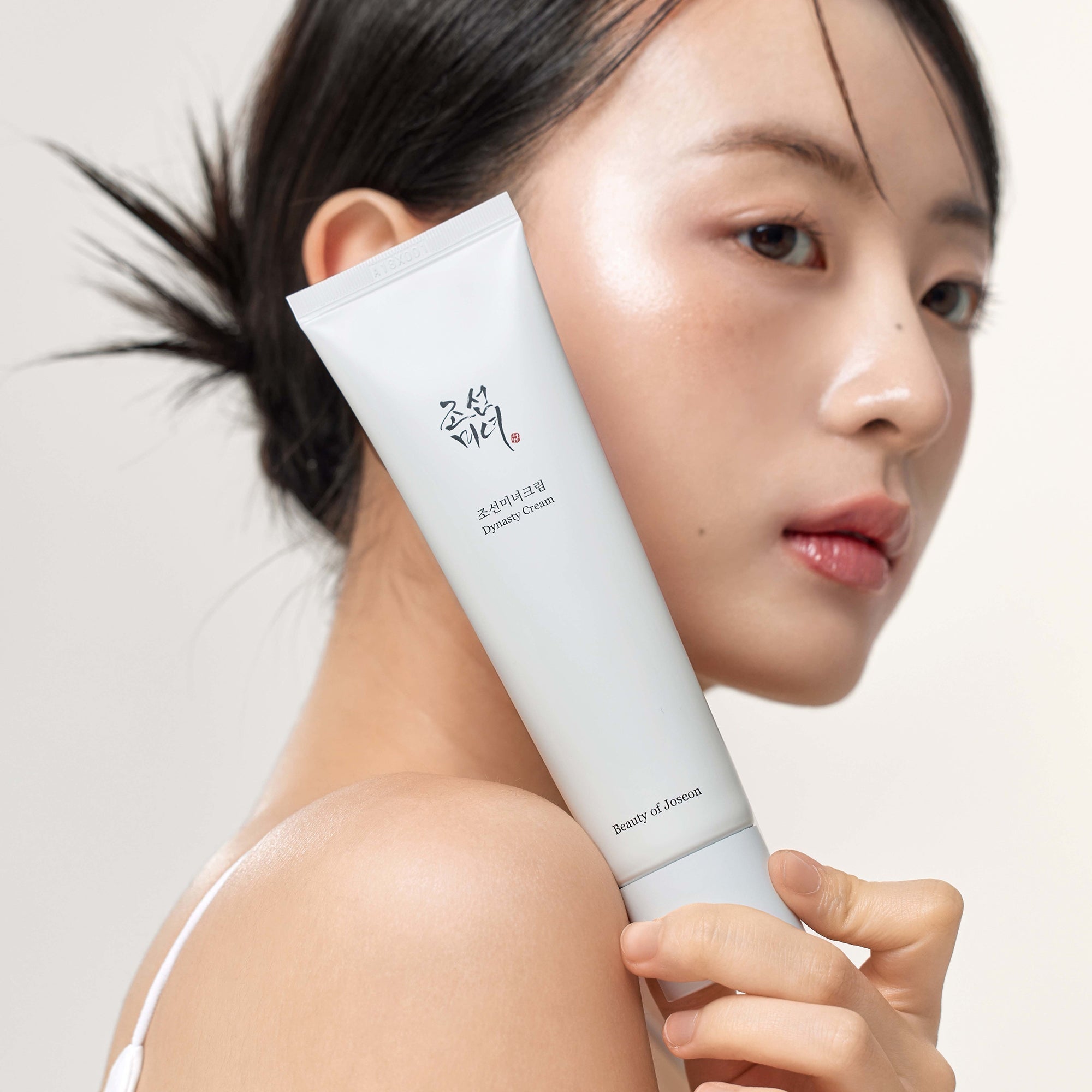 Woman holding BEAUTY OF JOSEON Dynasty Cream 100ml next to her face