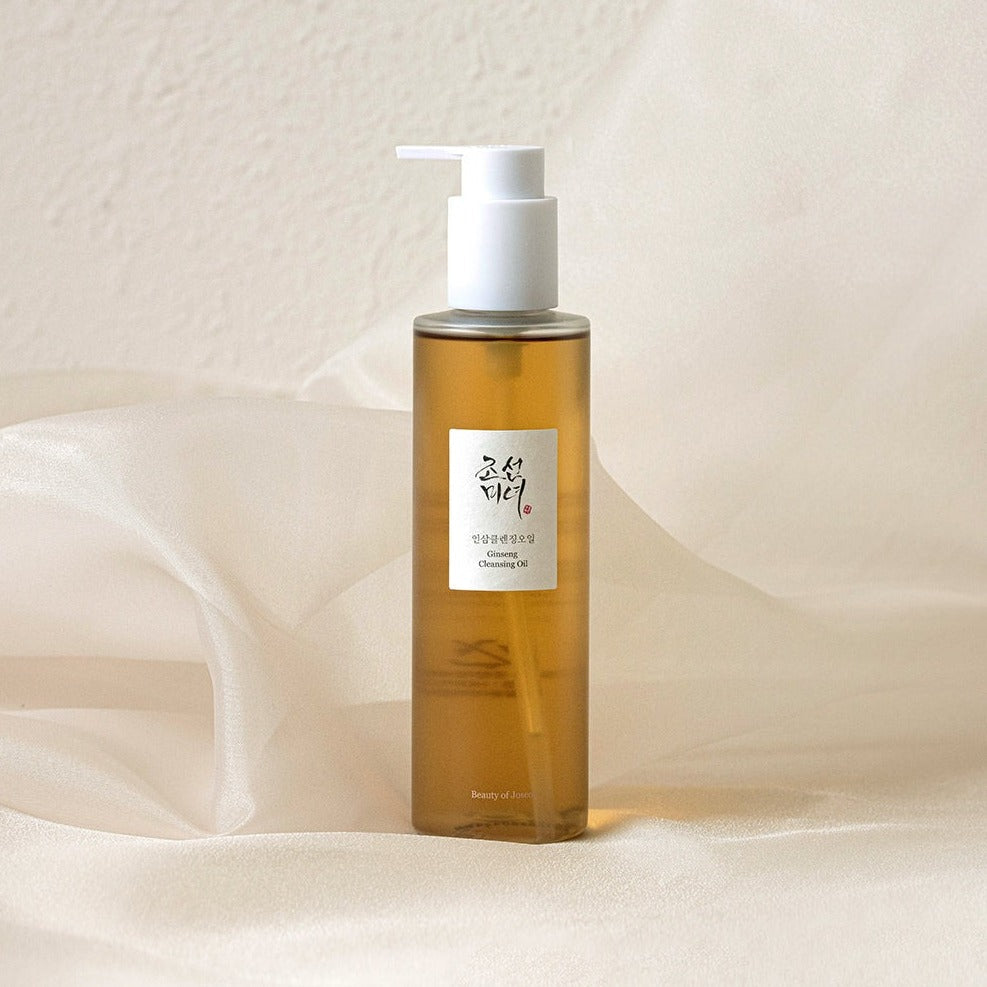 A bottle of BEAUTY OF JOSEON Ginseng Cleansing Oil 210ml on a soft fabric background.