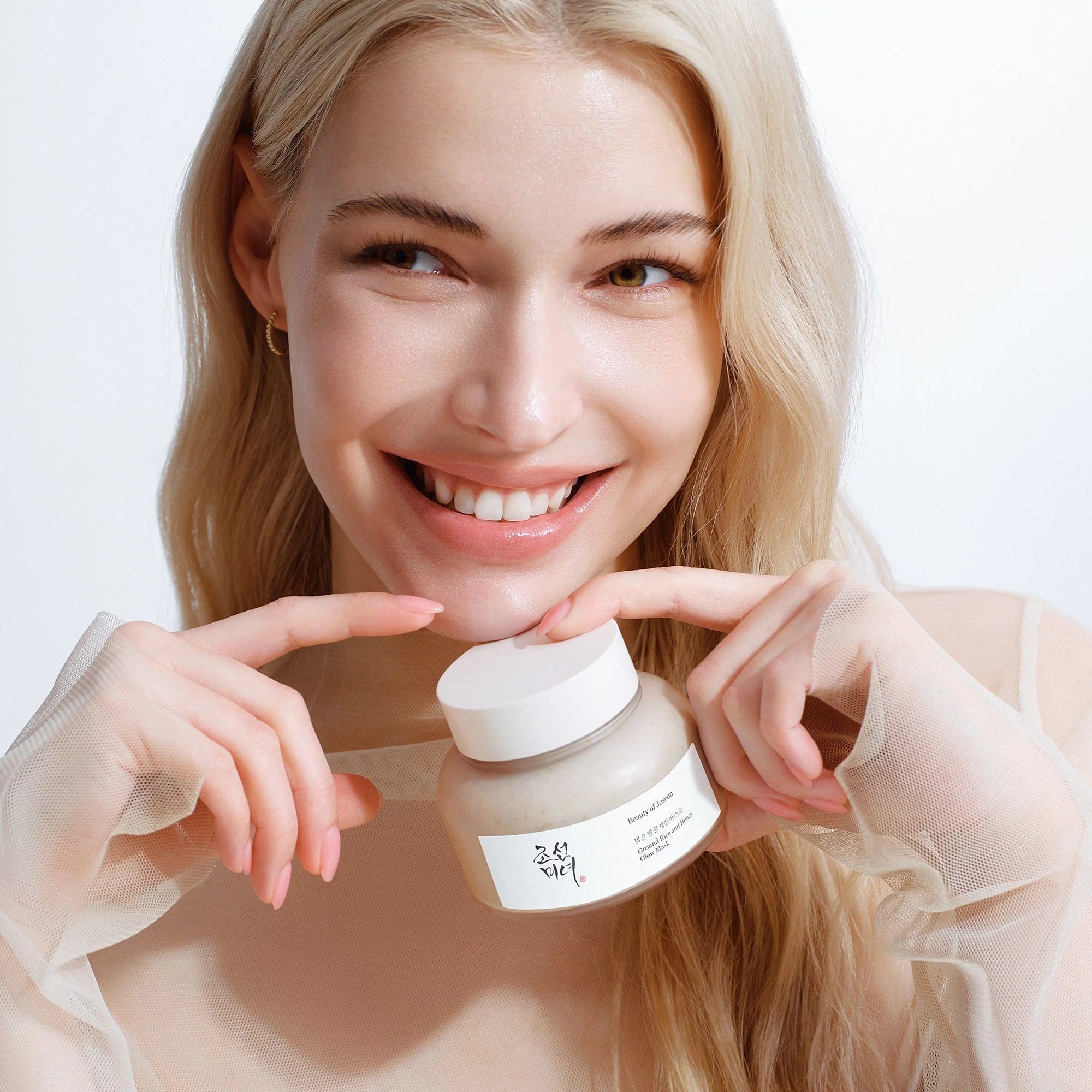 Woman holding BEAUTY OF JOSEON Ground Rice and Honey Glow Mask 150ml with a smile