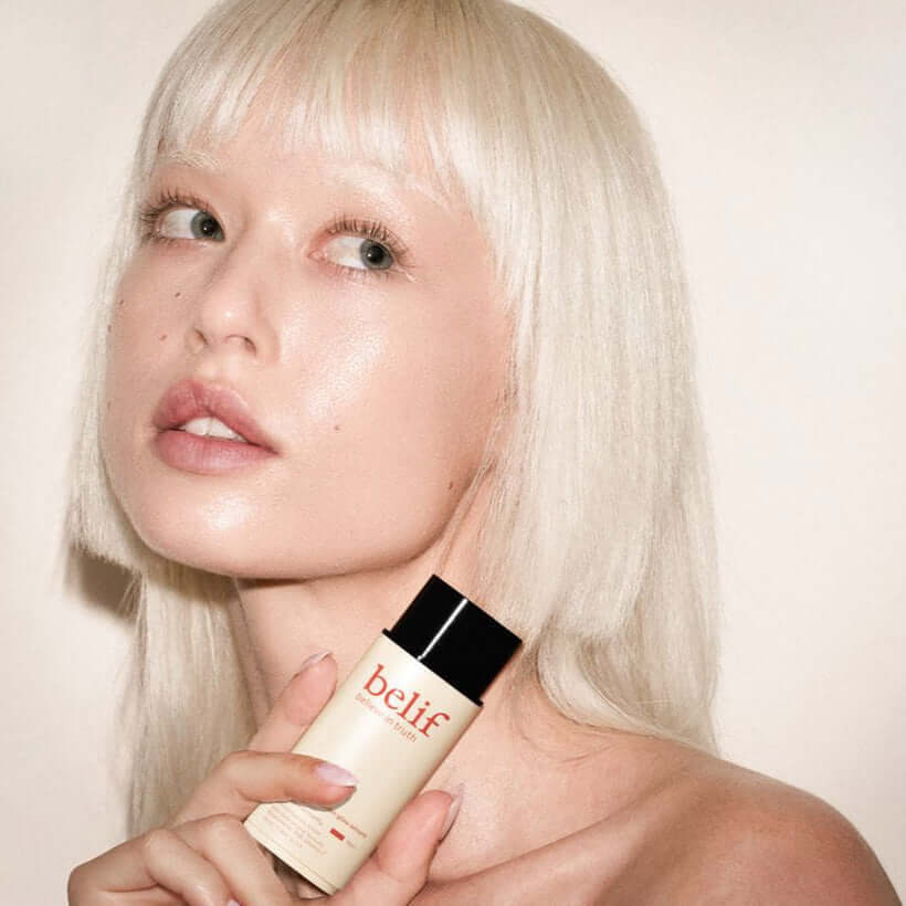 Model holding BELIF Super Drops Glow Serum 50ml for a radiant skincare routine.
