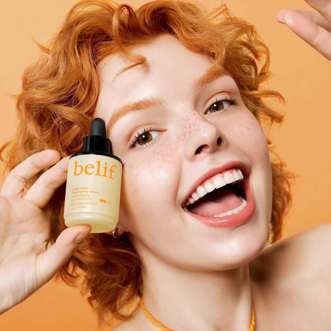 Woman smiling while holding BELIF Super Drops Vita C Toning Serum 30ml bottle