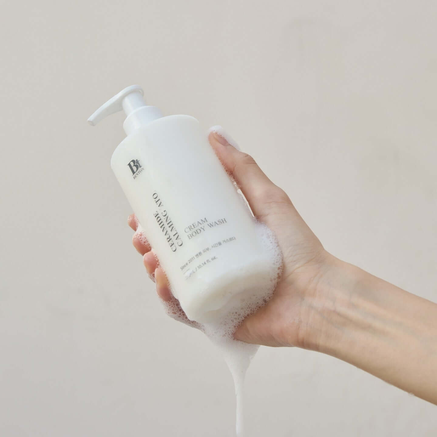 Hand holding BENTON Ceramide Calming Ato Cream Body Wash 300ml lathered in foam