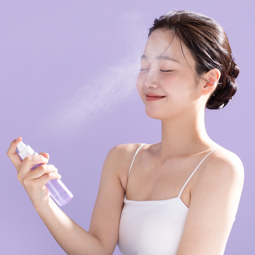Woman using BENTON Guava Hydrating Collagen Mist 100ml on her face against a purple background.