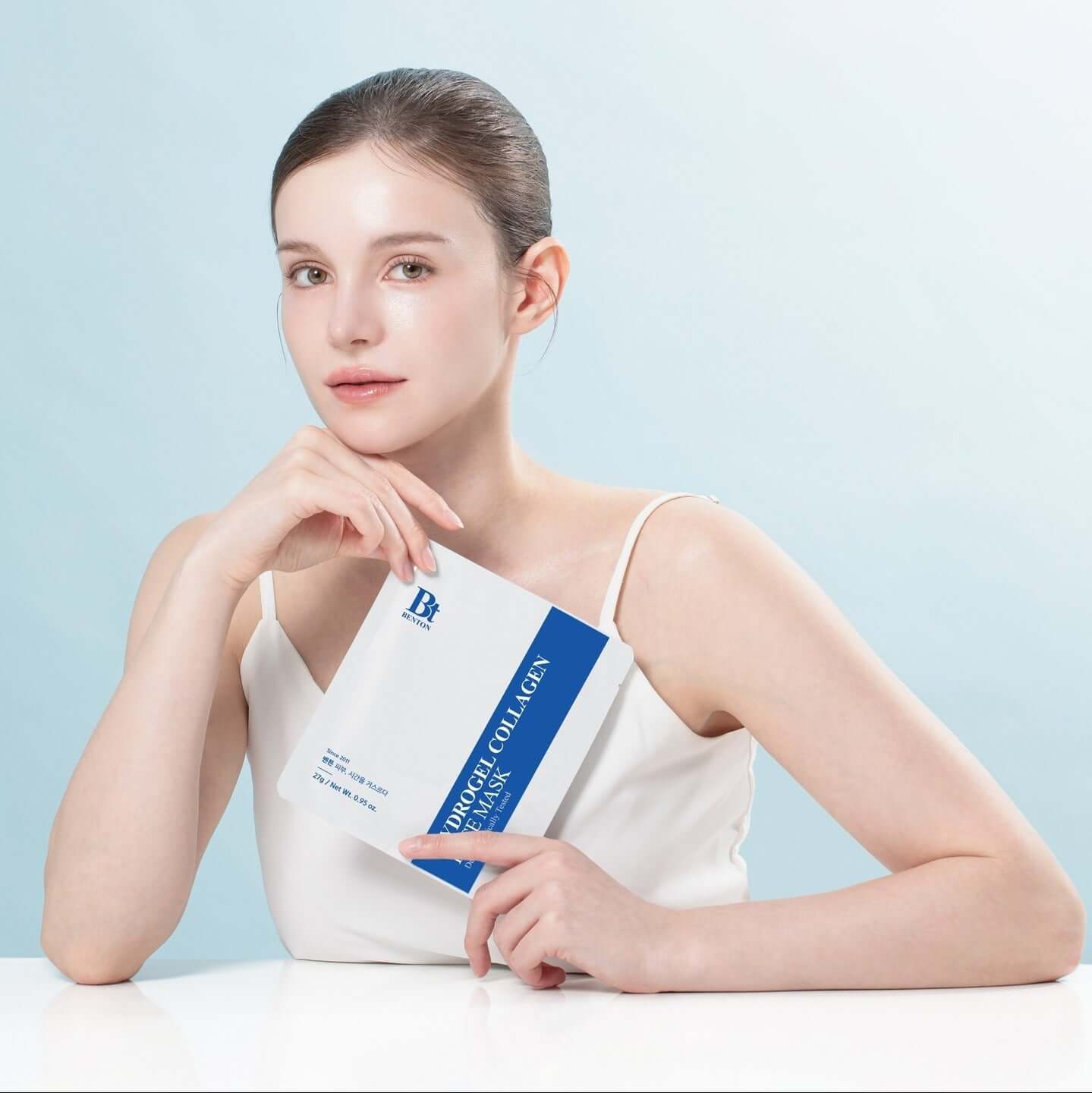 BENTON Hydrogel Collagen Mask Pack 27g x4 held by a woman in a white tank top against a light blue background