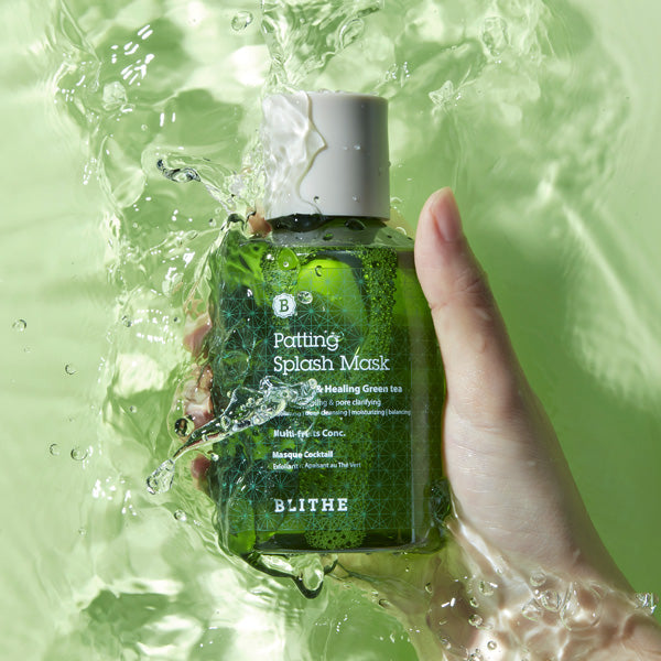Hand holding BLITHE Patting Splash Mask Soothing & Healing Green Tea 70ml/150mlm/300ml with water splashing around.