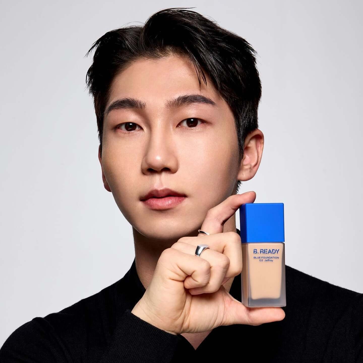 Gentleman Korea model holding B.READY Blue Foundation bottle with blue cap, natural men’s makeup for a polished gentleman look