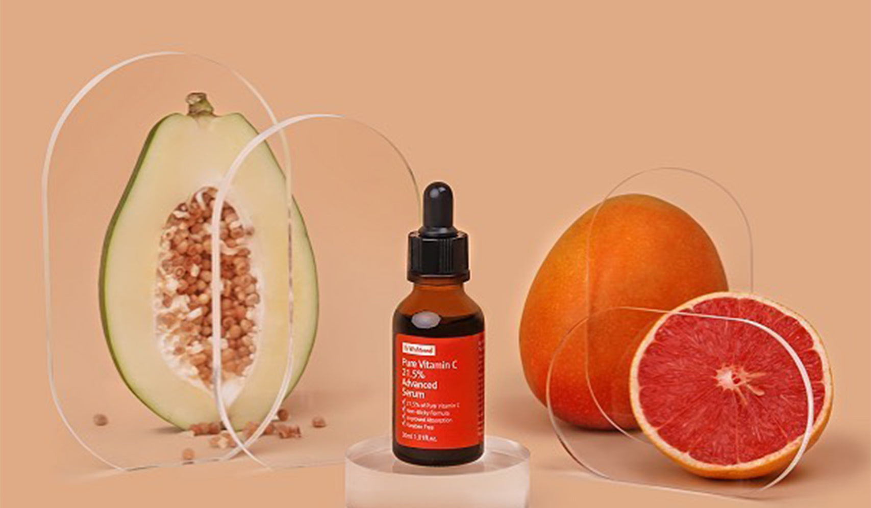 Vitamin C serum bottle with avocado and grapefruit slices on peach background