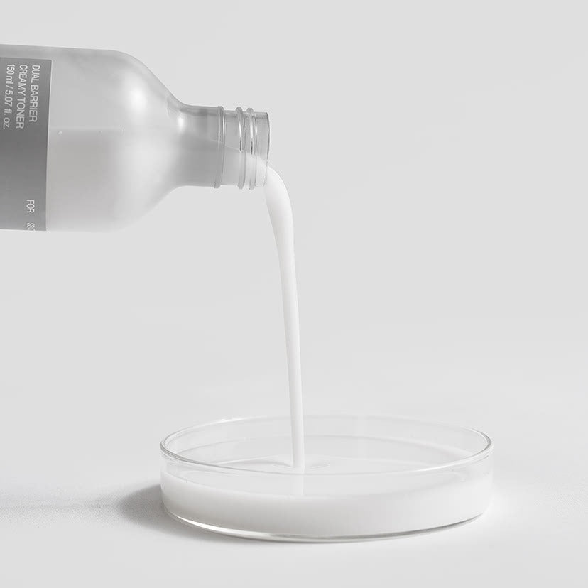 CELIMAX Dual Barrier Creamy Toner 150ml being poured into a clear dish on a white background, highlighting its creamy texture.
