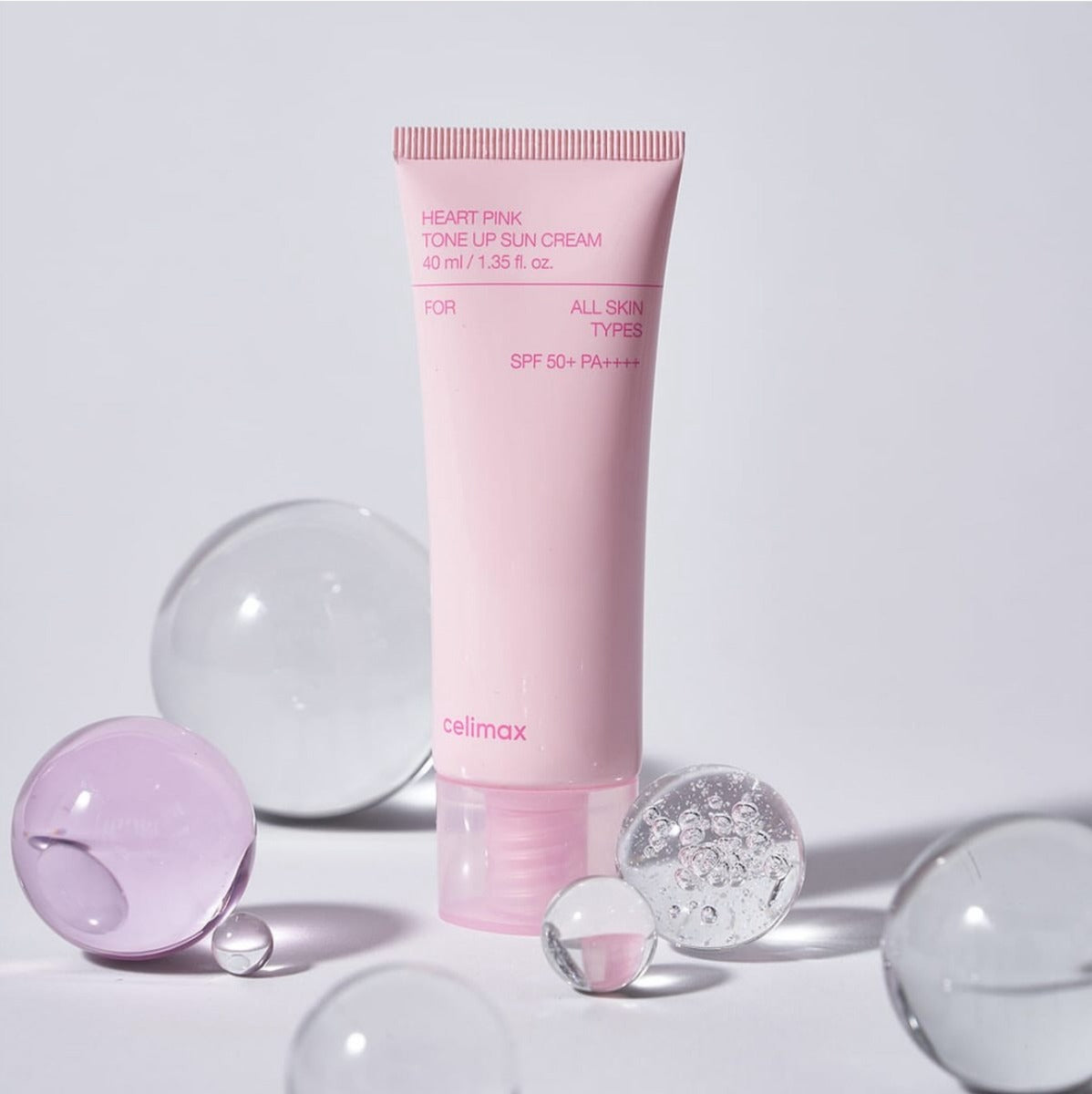 CELIMAX Heart Pink Tone-up Sun Cream 40ml with SPF 50+ surrounded by glass spheres.