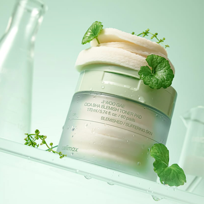 CELIMAX Ji Woo Gae Cica BHA Blemish Toner Pad 60 pads in a stylish green jar, surrounded by natural plant elements.