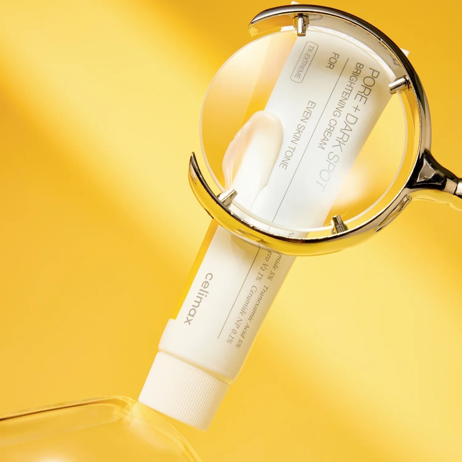 CELIMAX Pore Dark Spot Brightening Cream 35ml under magnifying glass on yellow background
