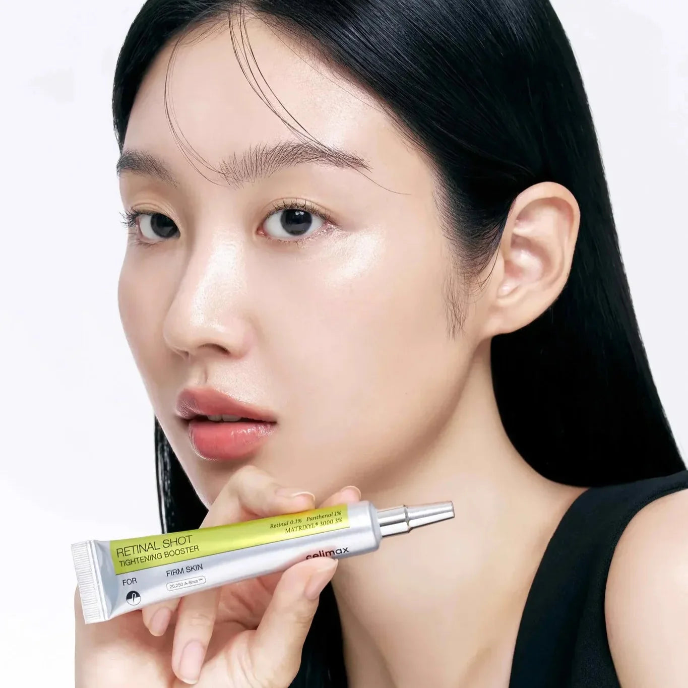 Woman holding CELIMAX Retinol Shot Tightening Booster 15ml, highlighting skincare benefits.