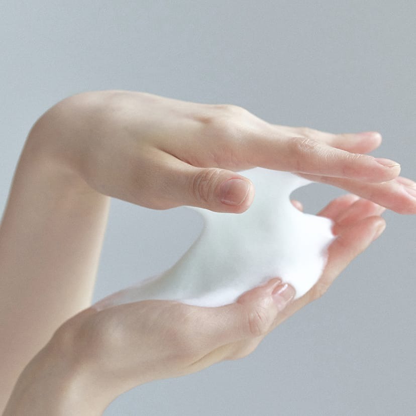 Hands holding foam from CELIMAX The Real Noni Acne Bubble Cleanser 155ml