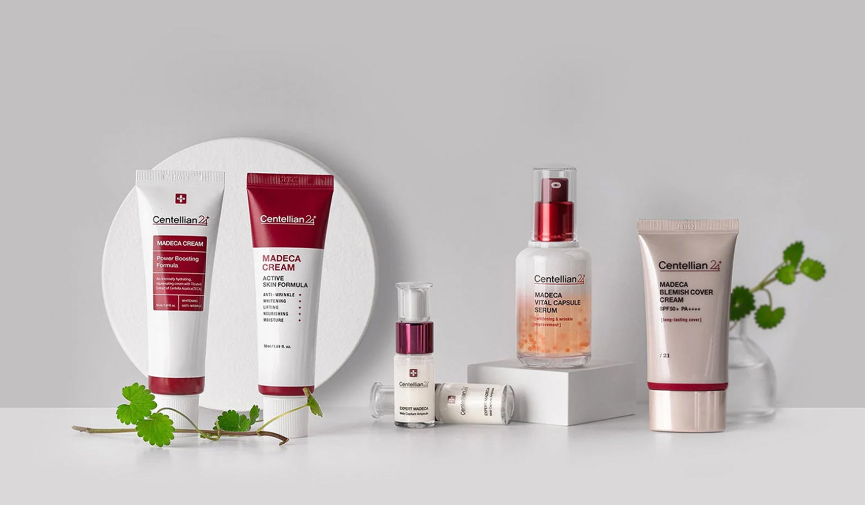 Centellian24 skincare products with tubes and bottles displayed on a white surface, featuring natural plant elements in the background.
