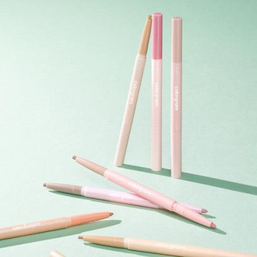 COLORGRAM All In One Aegyo-Sal Maker beauty pens on a green background, showcasing makeup tools for under-eye enhancement.