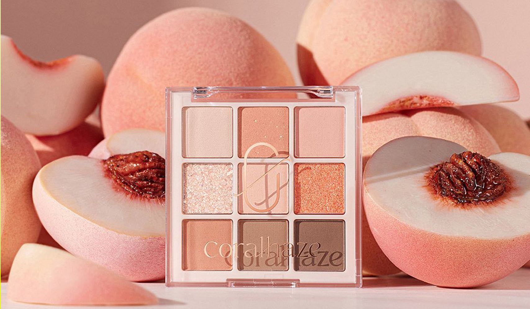 Peach-toned eyeshadow palette with fresh peaches in the background, showcasing various shades of warm, shimmery, and matte colors.