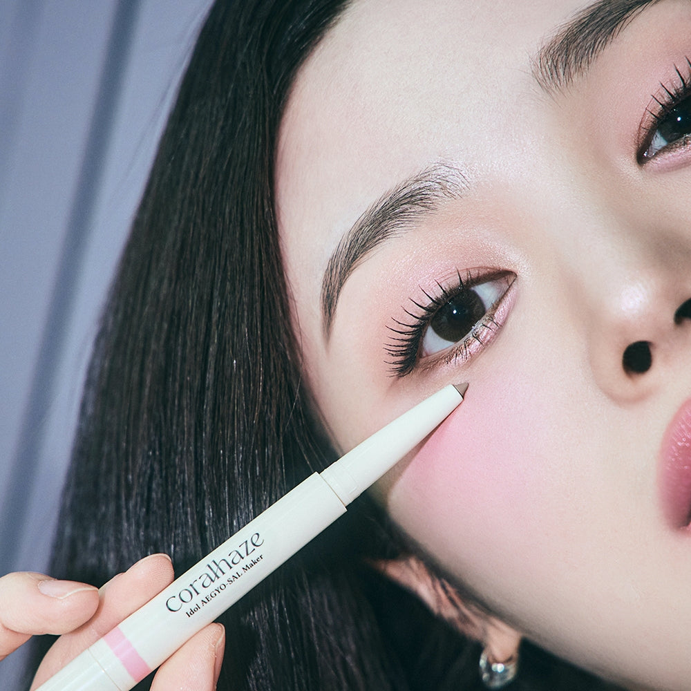 Close-up of a woman using CORALHAZE Idol Aegyo Sal Maker for enhanced under-eye definition.