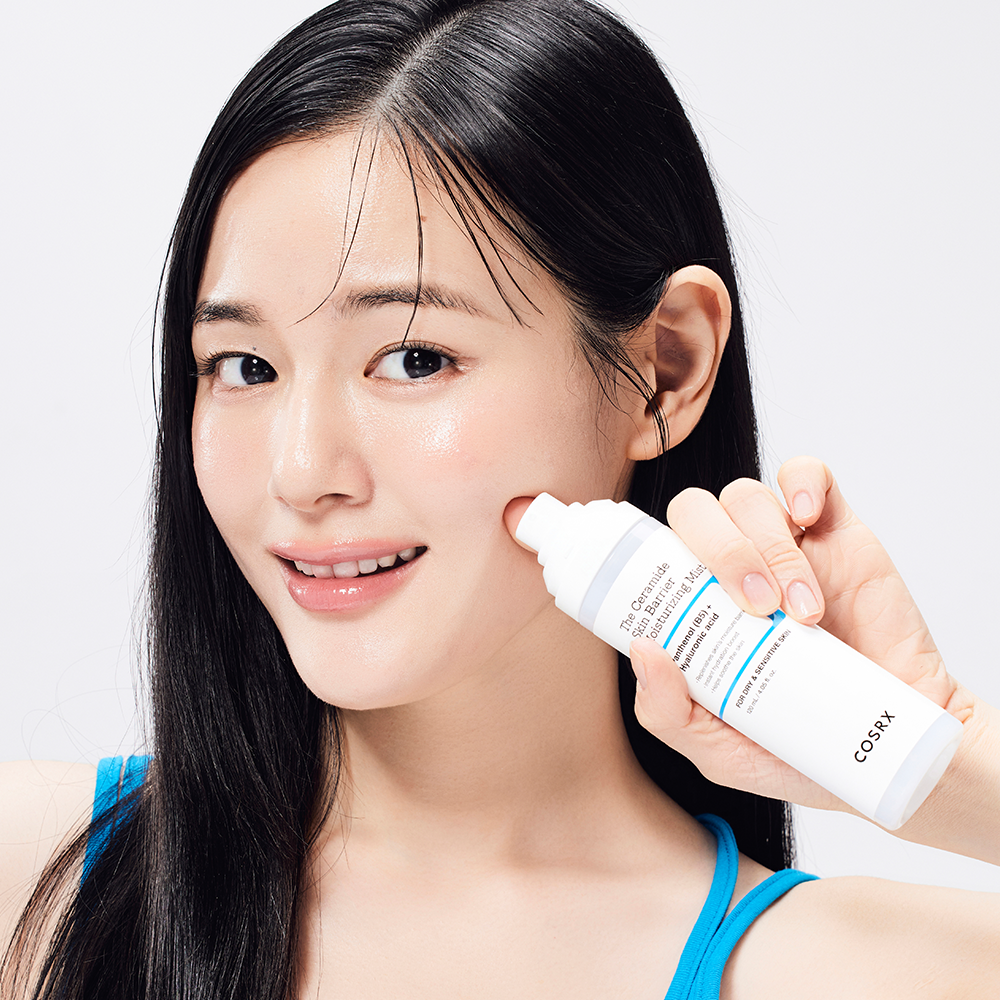 Young woman applying COSRX The Ceramide Skin Barrier Moisturizing Mist 120ml to her face for hydration and skin barrier support.