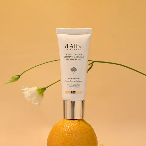 D'ALBA Aromatic Double Hand Cream 50ml placed on an orange, with a neutral background and a white flower