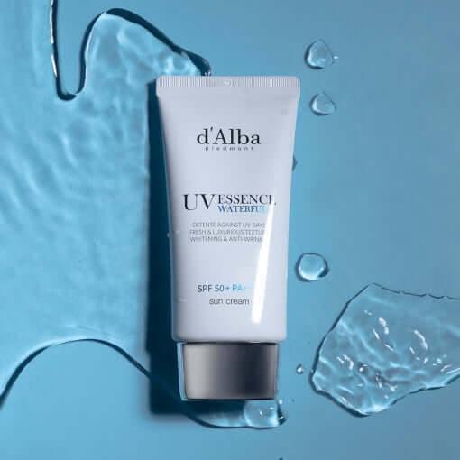 D'ALBA Vegan Waterfull Essence Suncream tube on blue background with water drops, showcasing sun protection and skincare benefits.