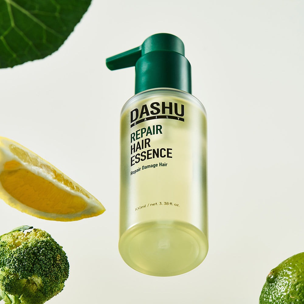 DASHU Daily Repair Hair Essence 100ml bottle with natural ingredients like lemon and broccoli for hair repair and nourishment.