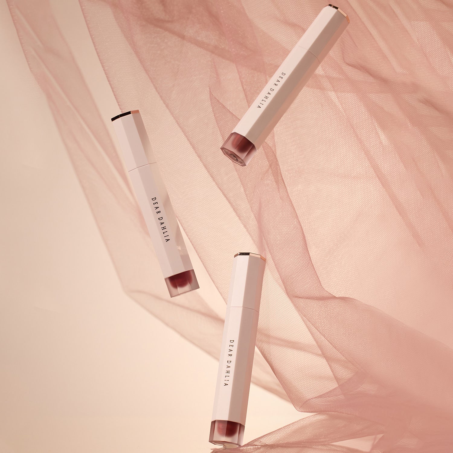 Three DEAR DAHLIA Dream velvet Lip Cloud tubes with pink fabric background