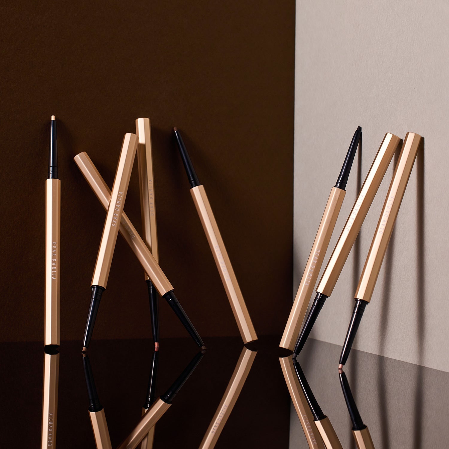 Multiple DEAR DAHLIA Perfect Desighning Eyeliner Pencil displayed artistically on a reflective surface.