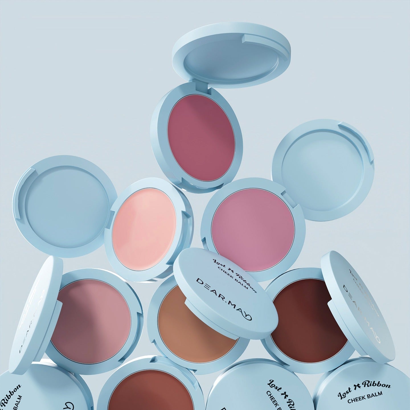 Open compacts displaying DEAR MAY Lost Ribbon Check Balm in various shades of pink and brown, showcasing elegant packaging and color range.
