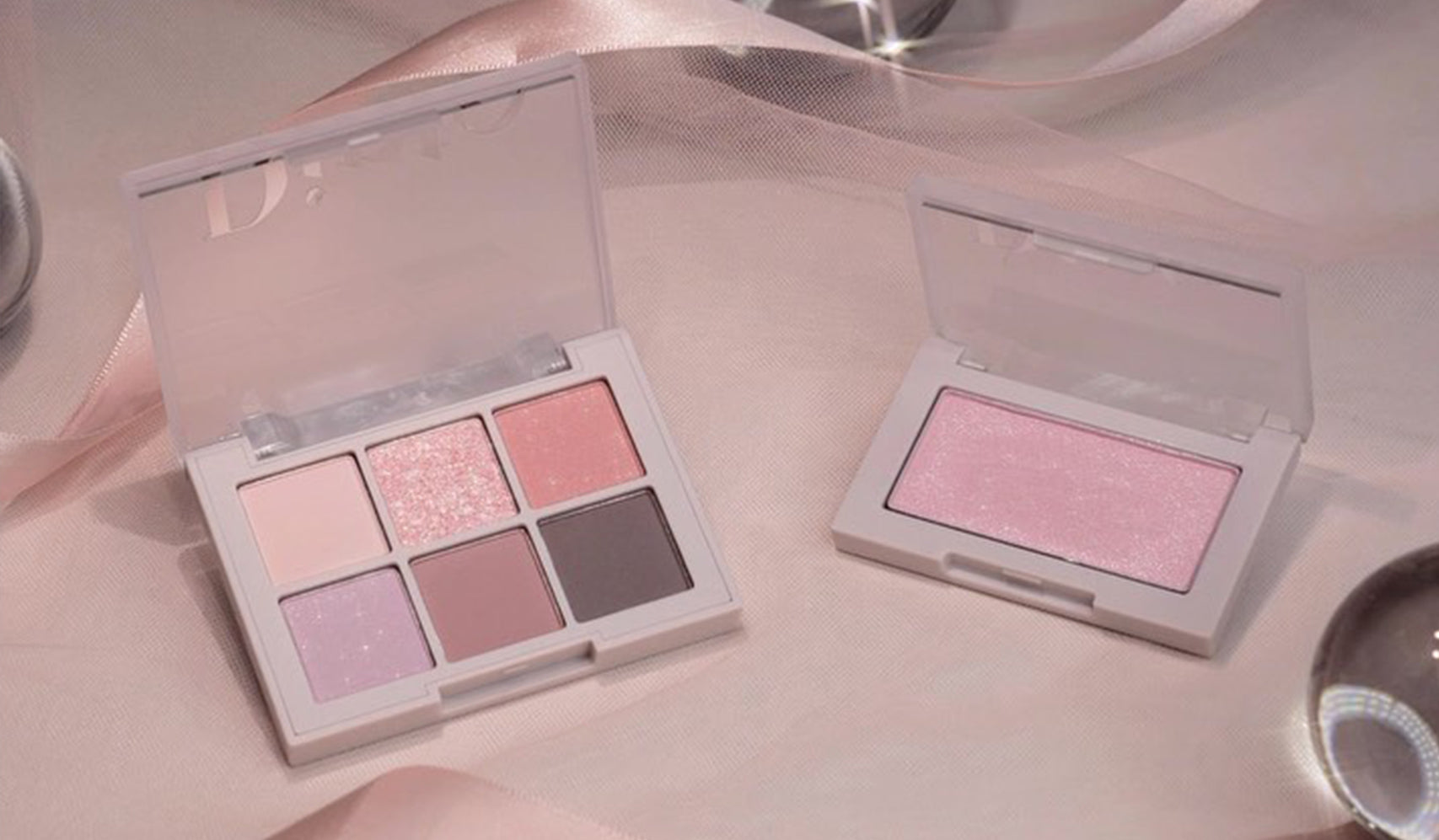 Soft pink and mauve eyeshadow palettes on a silky background with a sleek design for elegant makeup looks.