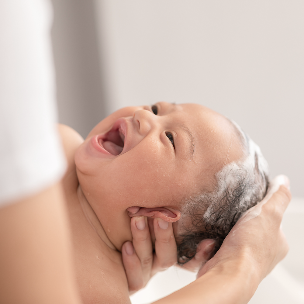 Baby smiling during bath with DONGGUBAT Correct Baby Soap Aloe, gentle hair wash, parent hands support.